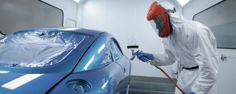 A mechanic spray-painting a car